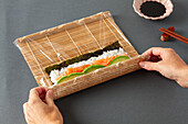 Making maki sushi with salmon and avocado