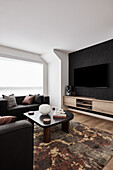 Modernes Wohnzimmer mit schwarzen Sofas und schwarzem Säulen-Couchtisch