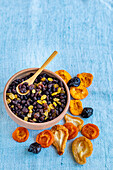 Dried fruits in a bowl and on a blue background