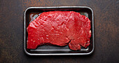 Raw beef steak in a black polystyrene tray