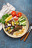 Falafel bowl with hummus, vegetables, olives, herbs and yoghurt sauce