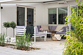 Terrasse mit Loungemöbeln und Pflanzen, darüber Markise