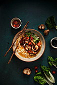 Rice noodles with mushrooms, bok choy and chili peppers in broth