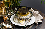 Schwarzer Kaviar auf Eis in Silberschale daneben Champagner
