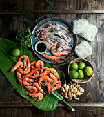 Zutaten für die thailändische Küche: Garnelen, Reisnudeln, Minze, Frühlingszwiebeln, Tintenfisch, Limetten