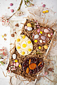 Schokoladen-Ostereier, dekoriert mit gemischten Bonbons, Nüssen und Trockenfrüchten
