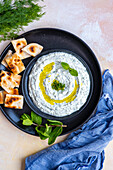 Türkischer Haydari-Meze-Dip mit frischen Minzblättern und Olivenöl, dazu Fladenbrot