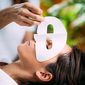 Beautician putting face mask on woman