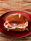 Italienisches Prosciutto-Sandwich mit Ciabatta-Laugebrötchen, frischem Mozzarella, Tomaten und Salat