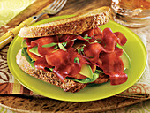 Whole wheat bread sandwich with soy bacon, avocado, tomatoes and lettuce leaf