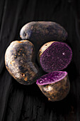 Whole and halved purple potatoes