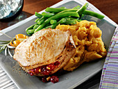 Roasted pork chop stuffed with cranberry chutney served with mashed sweet potatoes and green beans