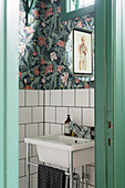 Waschbecken, florale Tapete und grüne Tür