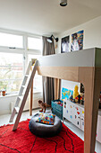 Loft bed with ladder, red carpet and decorations in children's room