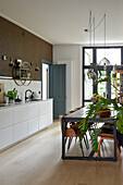 Modern kitchen with grey table, designer chairs and hanging lamps in front of floor-to-ceiling windows