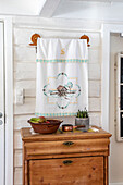 Wall hanging with embroidery above antique wooden chest of drawers