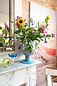 Colorful bouquet of flowers in blue vase on mantelpiece