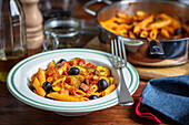 Pasta with bacon, zucchini and olives in tomato sauce