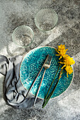 Minimalist table decoration with turquoise blue plate and daffodils