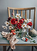 Blumenstrauß mit Rosen und Hagebutten in Glasvase