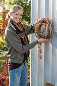 Autumn wreath made from pruning vine and Chinese reed with lantern flowers (physalis), poppy pods and rose hips