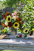 Blumenstrauß mit Sonnenblumen (Helianthus), Rosen (Rosa), Brokkoli, Wilde Möhre, Fuchsschwanz (Amaranthus) auf Gartentisch