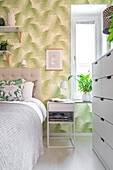 Bedroom with plant wallpaper, bed, wardrobe and shelves