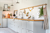 Scandinavian-style kitchen with light grey cabinets, wooden counter and metro tiles