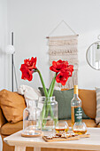 Amaryllis in a vase on a wooden table with Christmas cookies and drinks