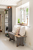 Rustic wooden bench with fur and cushions, wooden floor shelf