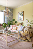 Living room with glass coffee table, monstera and spring flowers