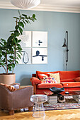 Living room with orange sofa, blue wall and large houseplant