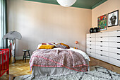 Bedroom with herringbone parquet flooring, bed and colorful accents