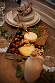 Platter with cheese, nuts, olives and dates wrapped in bacon on a rustic wooden table