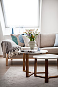 Bright living room with sofa, woollen blanket and round side tables