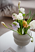 Flower arrangement with ranunculus and hyacinths in a grey vase