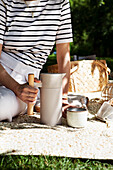 Picnic in the park with thermos flask and ceramic mug on the blanket