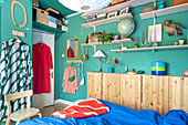 Open shelves, including narrow wooden wardrobe in bedroom with blue walls