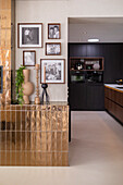 Gallery wall with photos in black and white, gold panelling and view into the kitchen