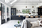 Open-plan kitchen with dining area and hanging pendant lights in black and white design