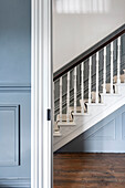 Staircase with white balusters and blue wall panels