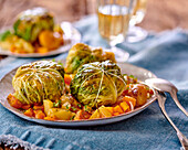 Savoy cabbage roulades filled with ground meat filling on a vegetable sauce with dried apricots