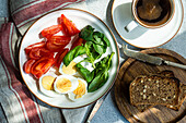 Gesundes Frühstück mit frischem Gemüse, gekochten Eiern, Brot und einer Tasse Kaffee