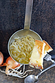 Onion soup in a ladle with cheese toast