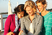 Three friends on a dock laughing