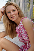 Blonde woman in pink and white summer dress on the beach