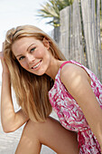 Blonde woman in pink and white summer dress on the beach