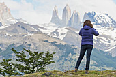 Eine Frau steht mit Blick auf die zerklüftete Berglandschaft, Torres Del Paine Nationalpark; Torres Del Paine, Magallanes und Antartica Chilena Region, Chile