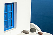 Weiß getünchtes Gebäude mit blau umrandeten Fenstern entlang der Ägäis; Oia, Santorin, Griechenland