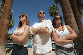 Two Young Women And A Man Standing By Palm Trees; Palm Springs, California, United States Of America